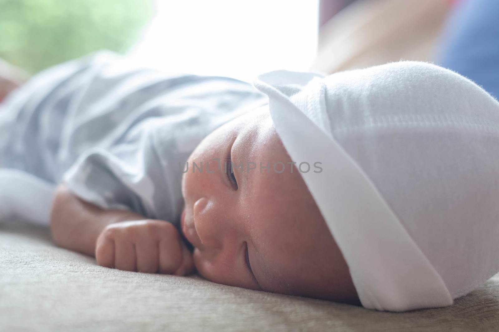 portrait of cute little baby infant  boy wearing white hat lay to sleep prone on the bed,