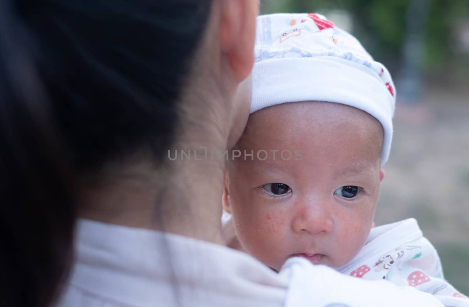 Portrait of a newborn baby infant  hold close by mother in the garden, close up. Family,