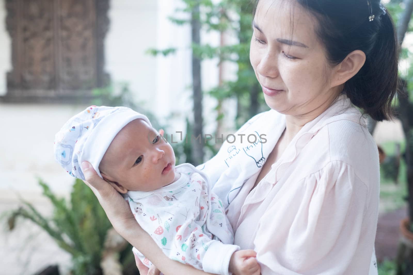 Portrait of a newborn baby infant  hold by mother in the garden, close up. Family,