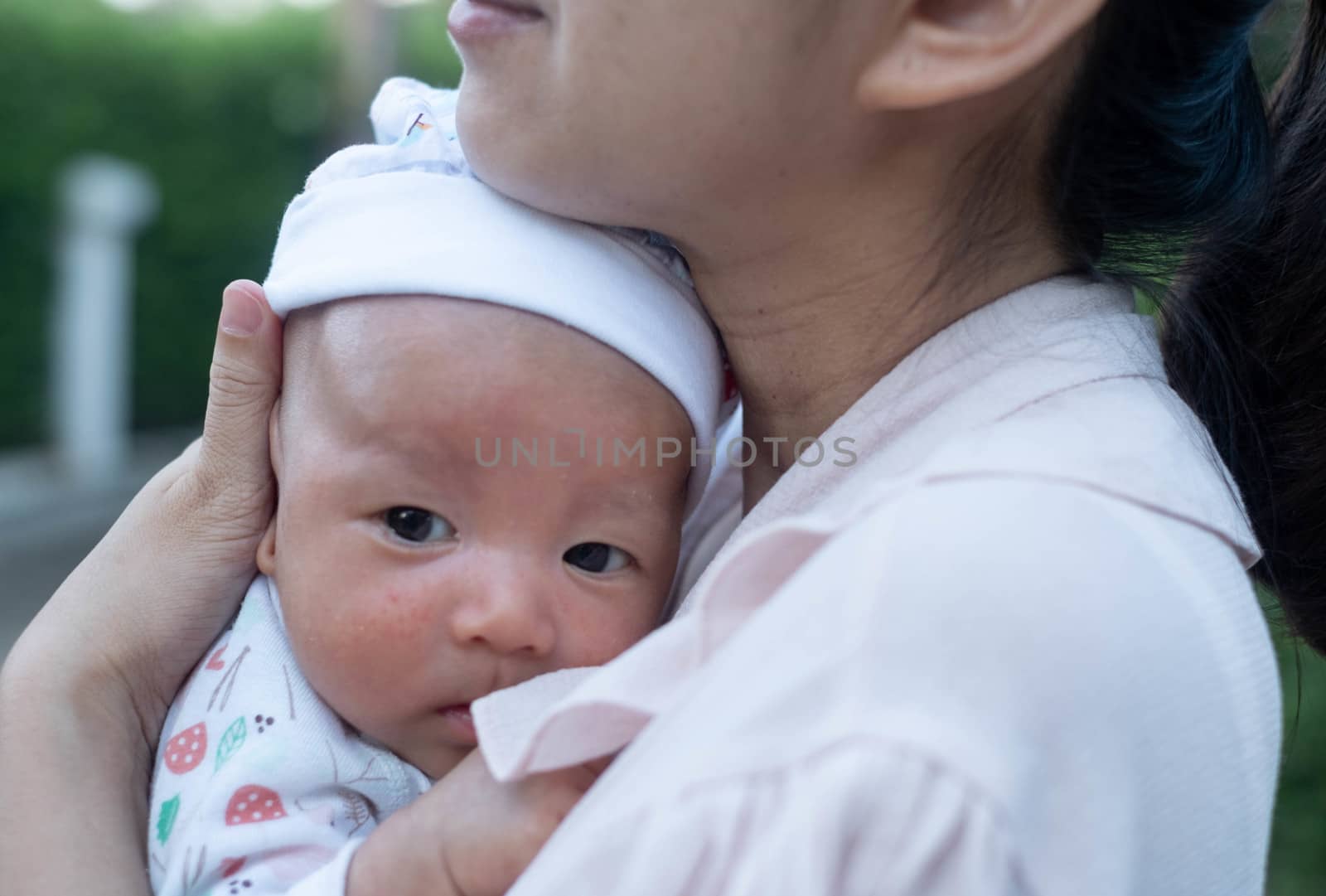 Portrait of a newborn baby infant  hold close by mother in the garden, close up. Family,