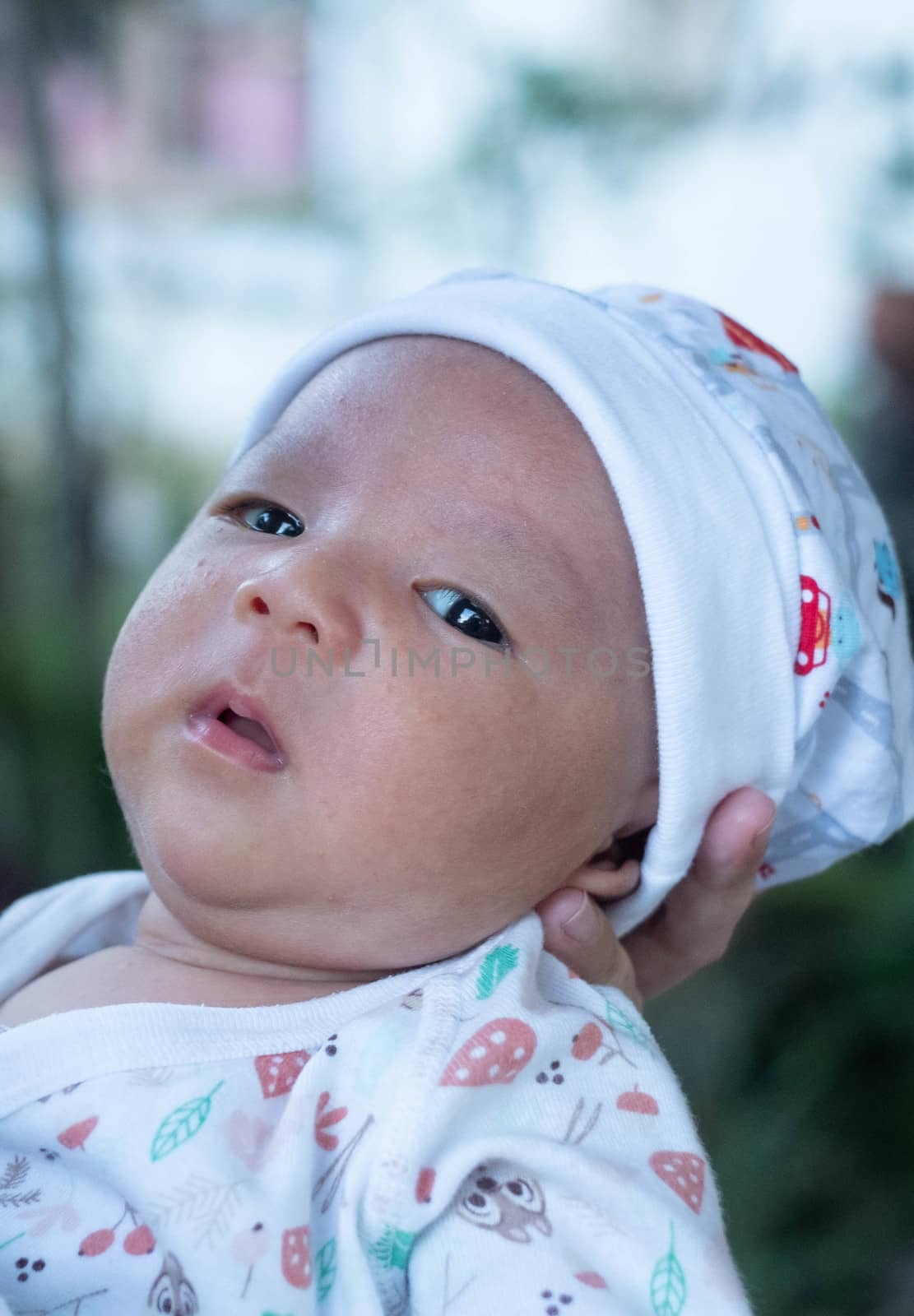 Portrait of a newborn baby infant  hold close by mother in the garden, close up. Family,