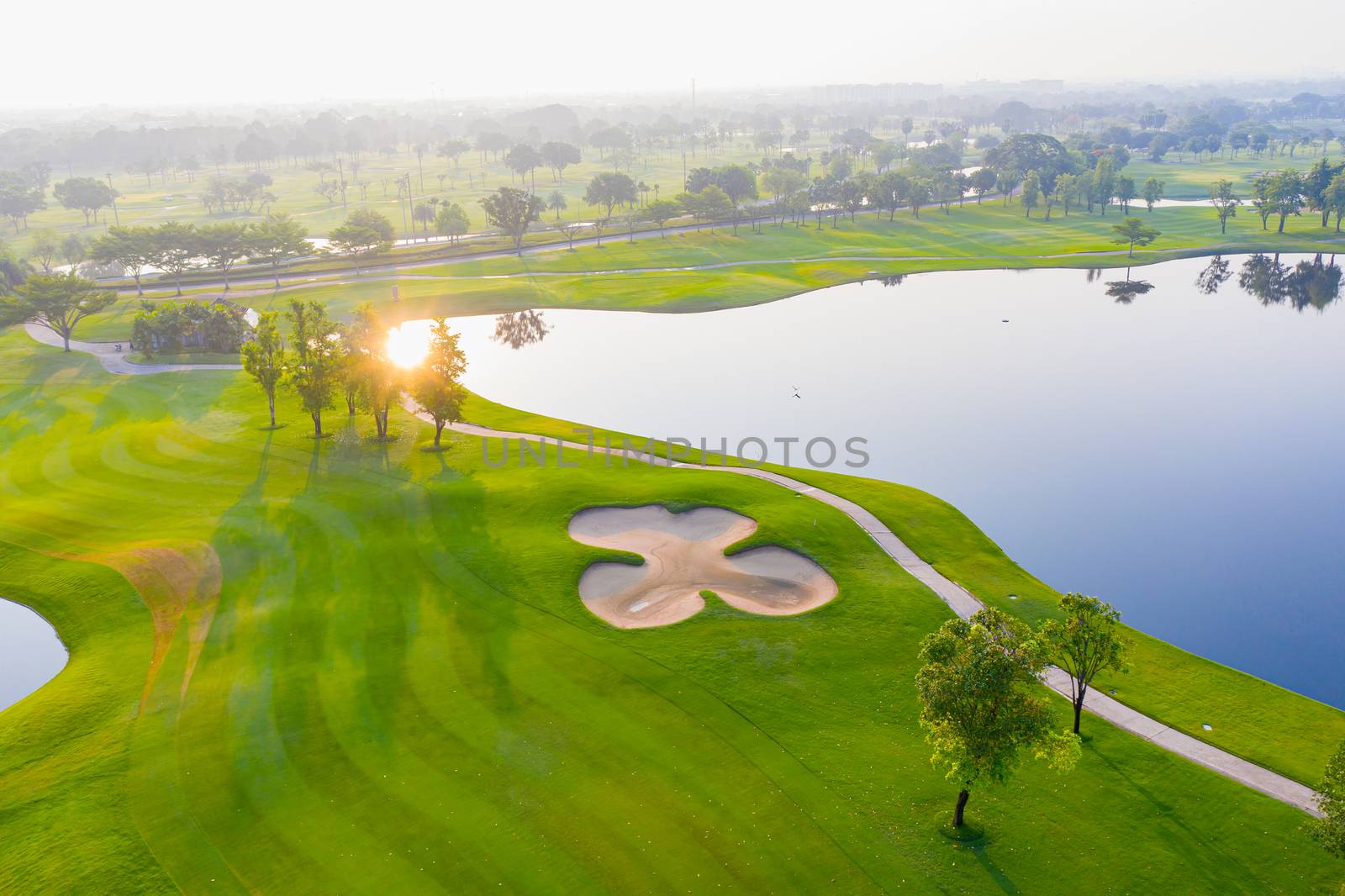Aerial view of golf field landscape with sunrise view in the mor by PlottyPhoto