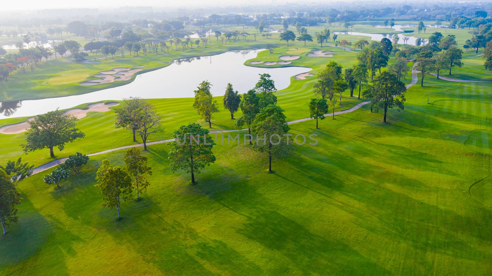 Aerial view of golf field landscape with sunrise view in the mor by PlottyPhoto