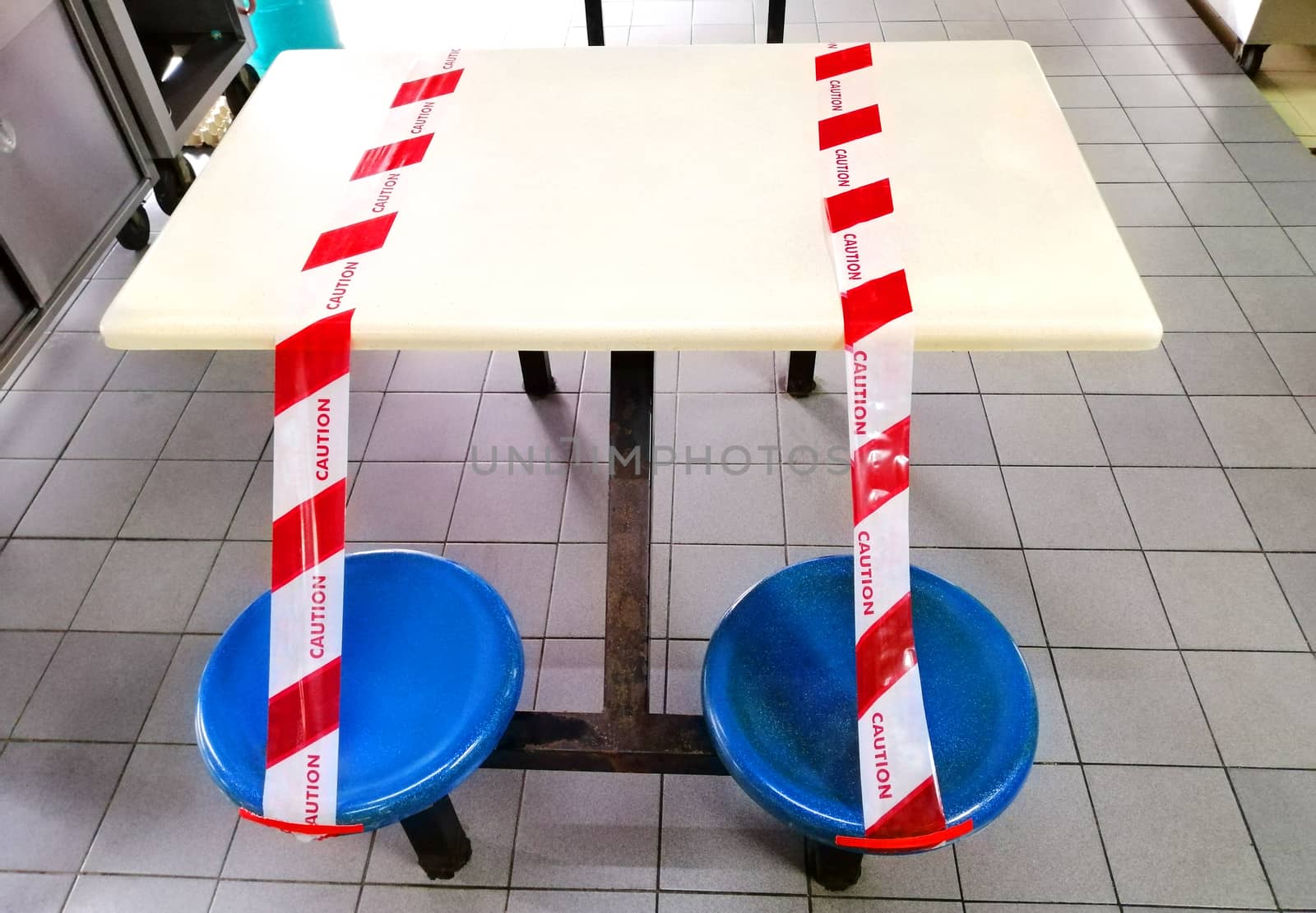 Red and white caution tape wrapped around outdoor tables and seats area of hawker centre in malaysia which closed for social distancing purpose to stop spreading coronavirus covid-19 . 