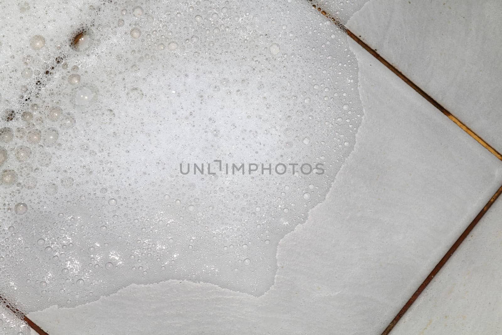 Bubbles soap detergent with scrubbing the bathroom floor dirt wet, Foam white bubble from shampoo washing on Tiled floor top view