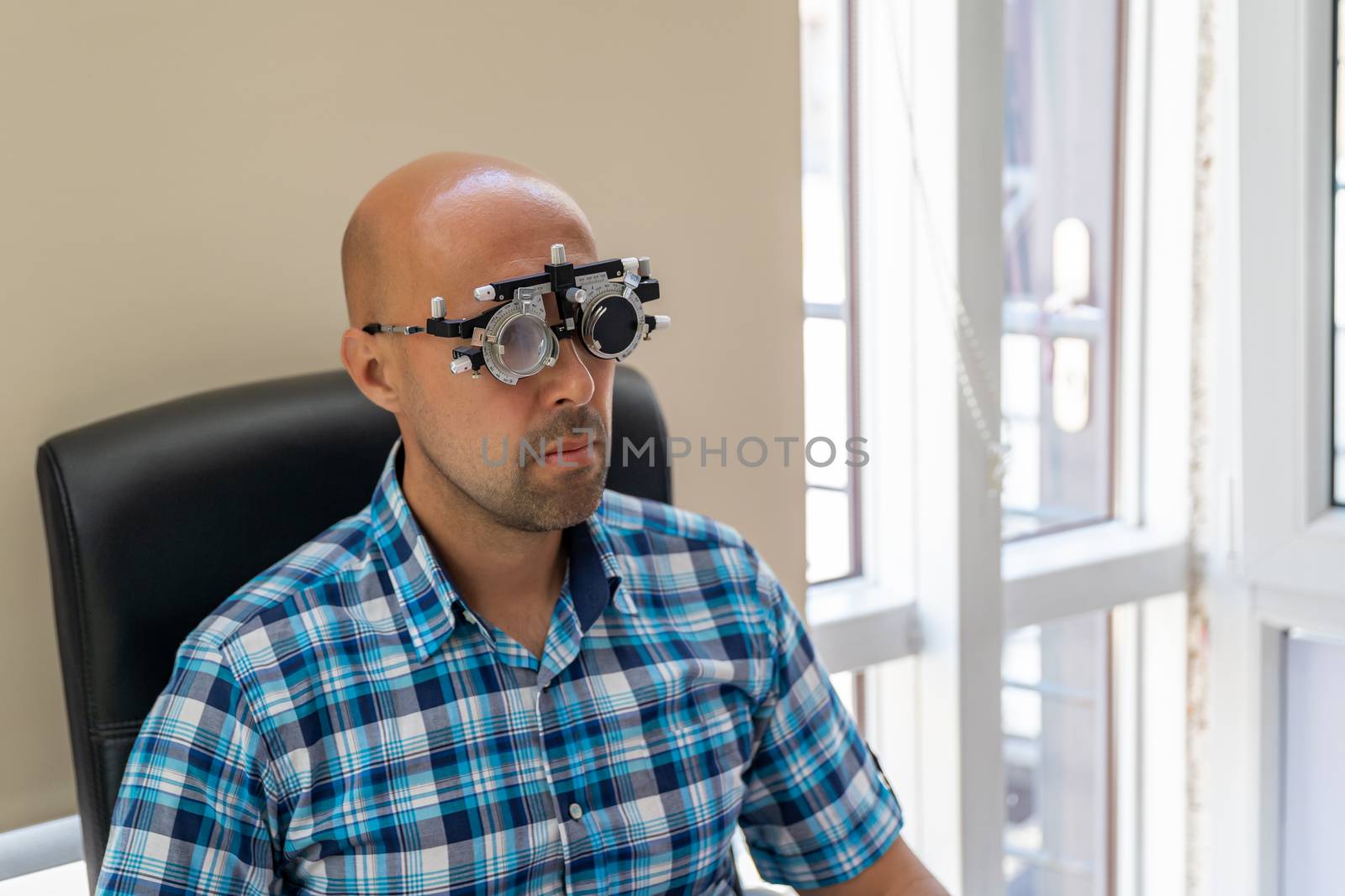 vision measurement by optometrist at clinic, young man as patient.