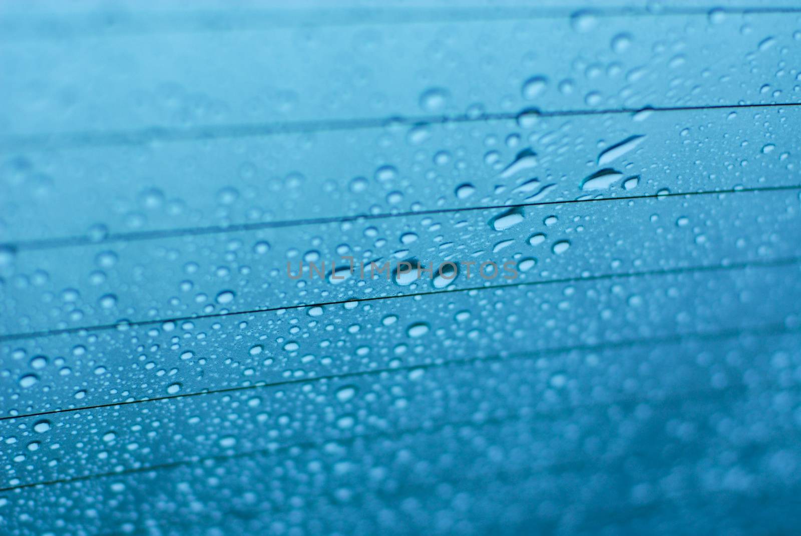 Water drops on glass window with blue background