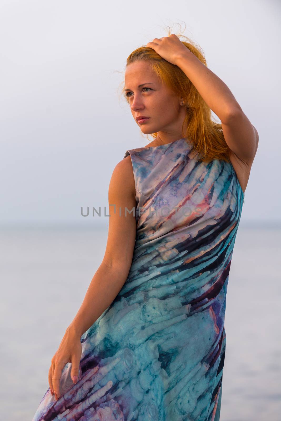 Young red woman wearing long dress on a beach