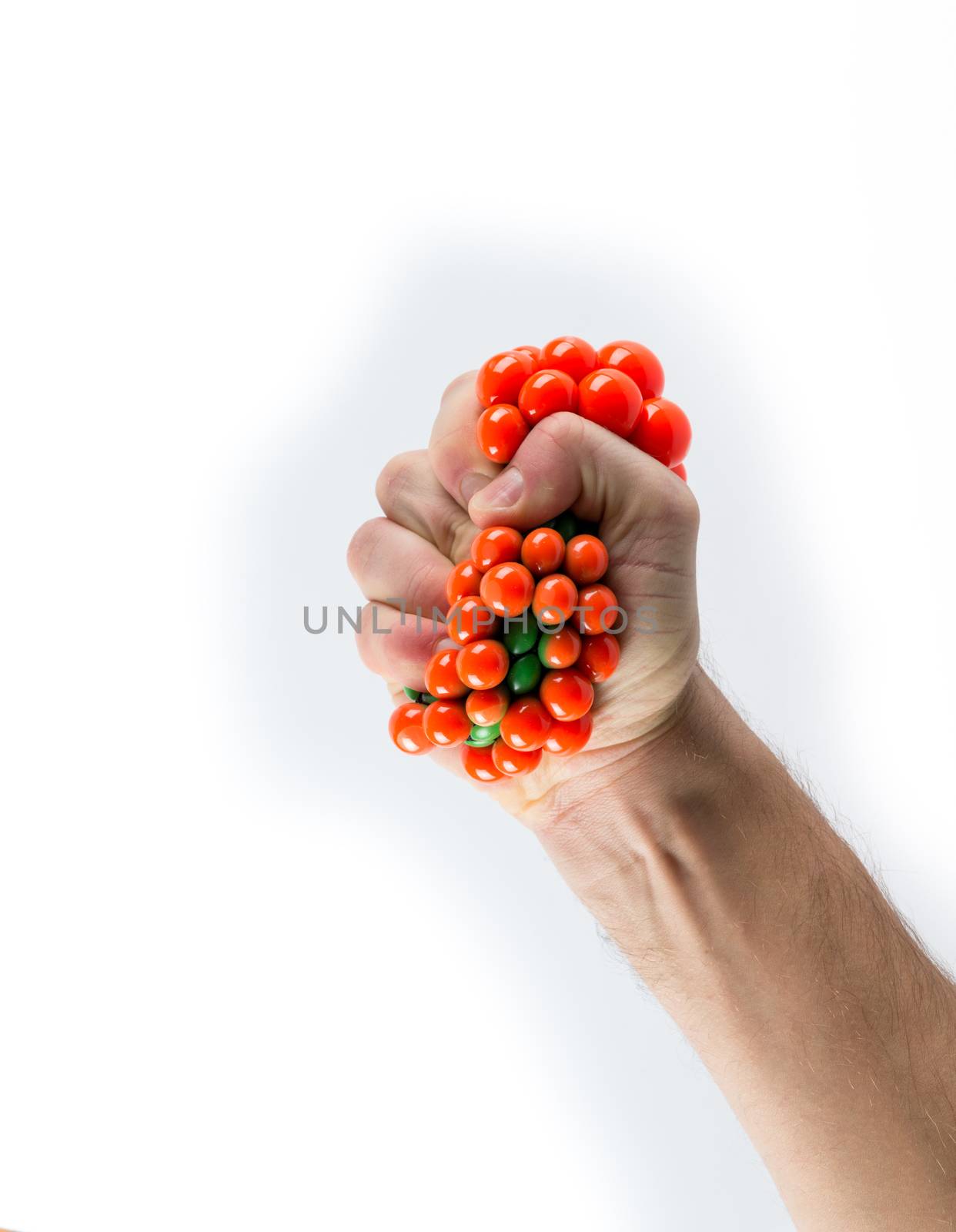 Male hand squeezing stress ball over plain background