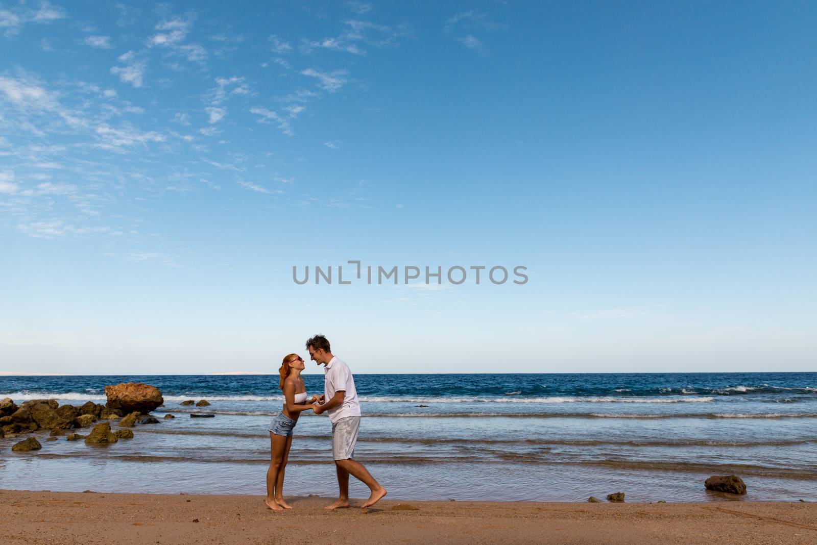 Romantic young couple walking on the beach with bare feet