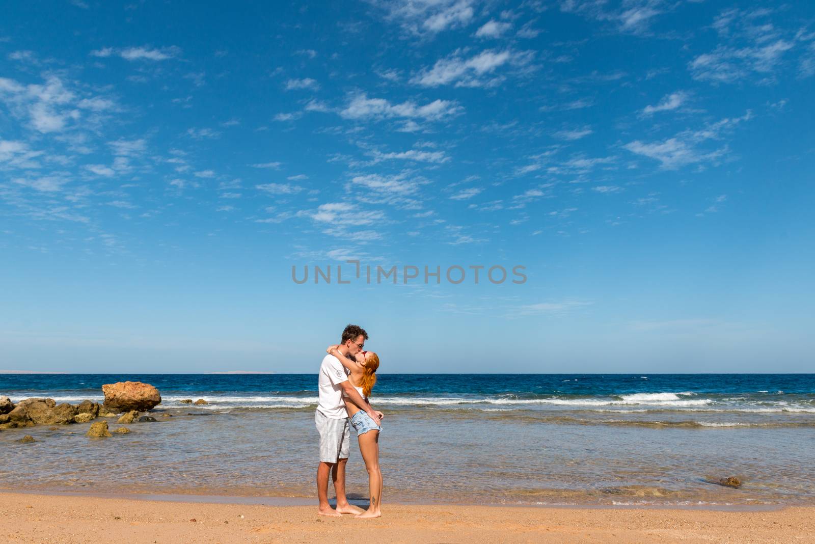 Romantic young couple walking on the beach with bare feet