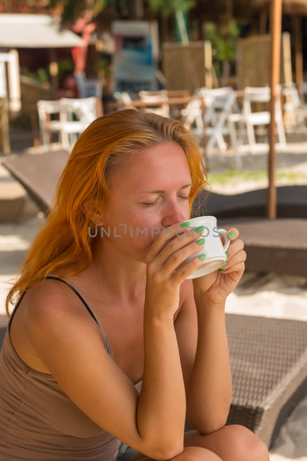 Young woman drinking coffee at beach in the morning