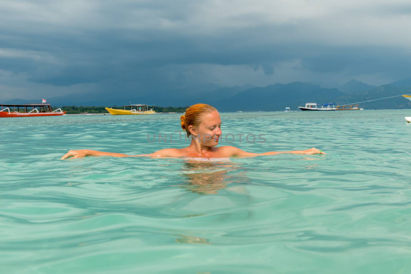 Woman at tropical island beach swimming in lush blue water