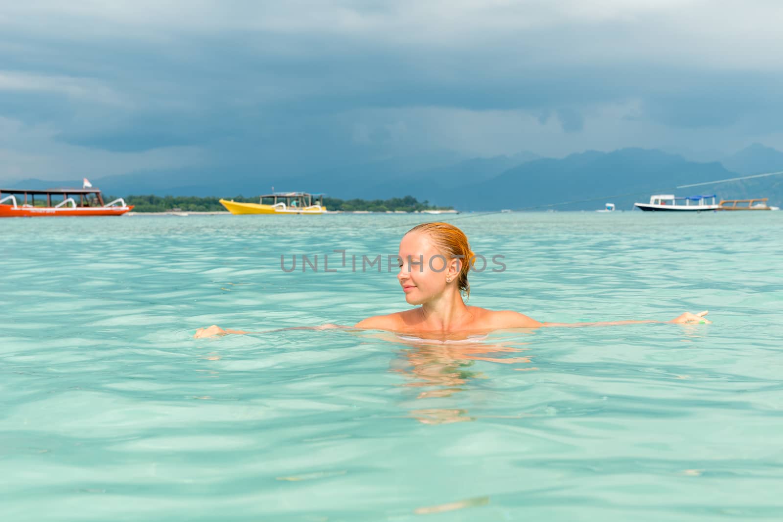 Woman at tropical island beach swimming in lush blue water