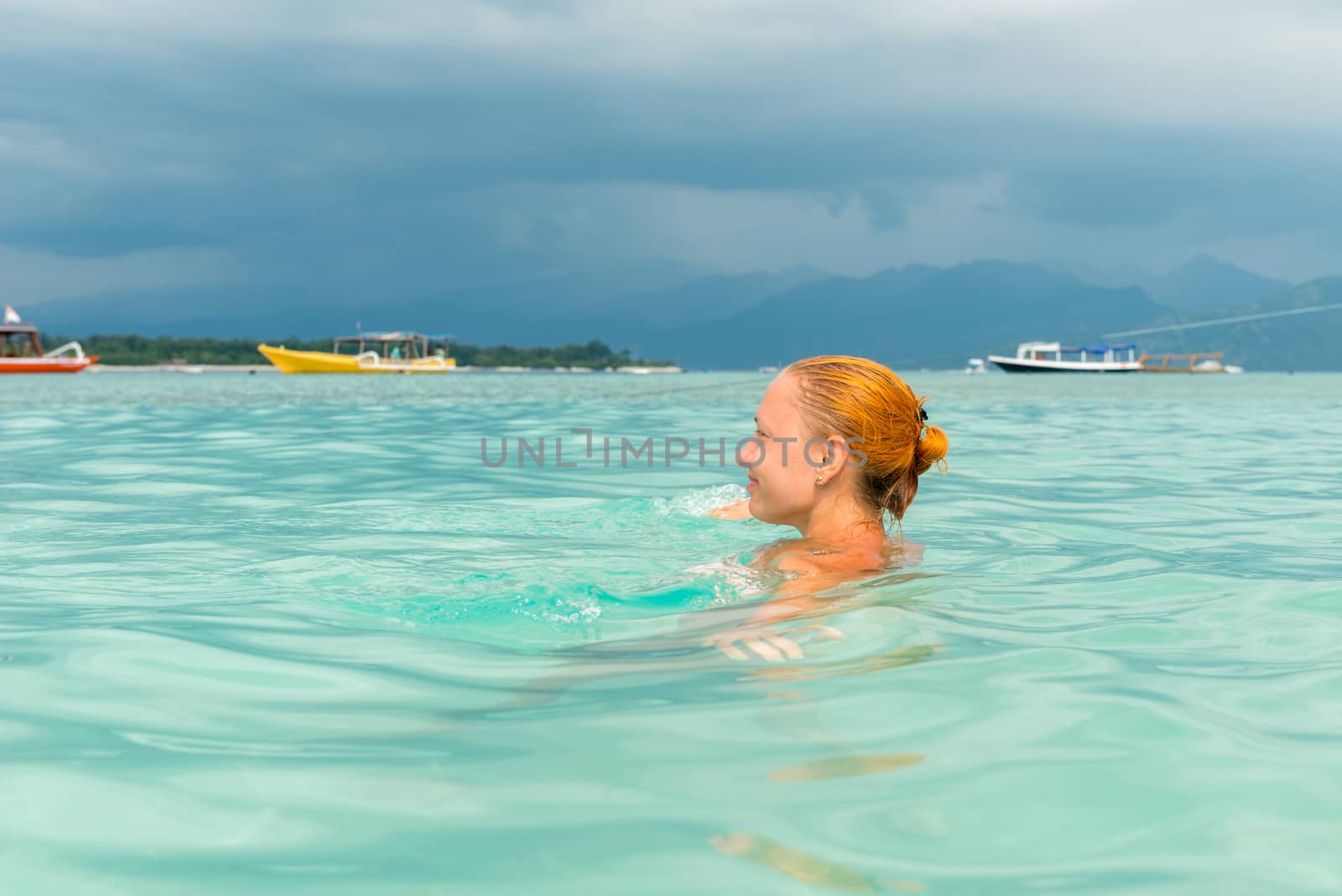 Woman at tropical island beach swimming in lush blue water