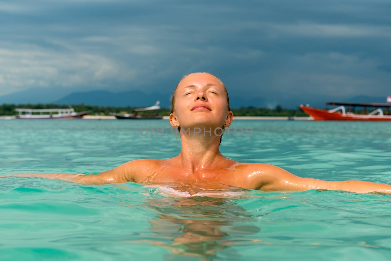 Woman at tropical island beach swimming in lush blue water