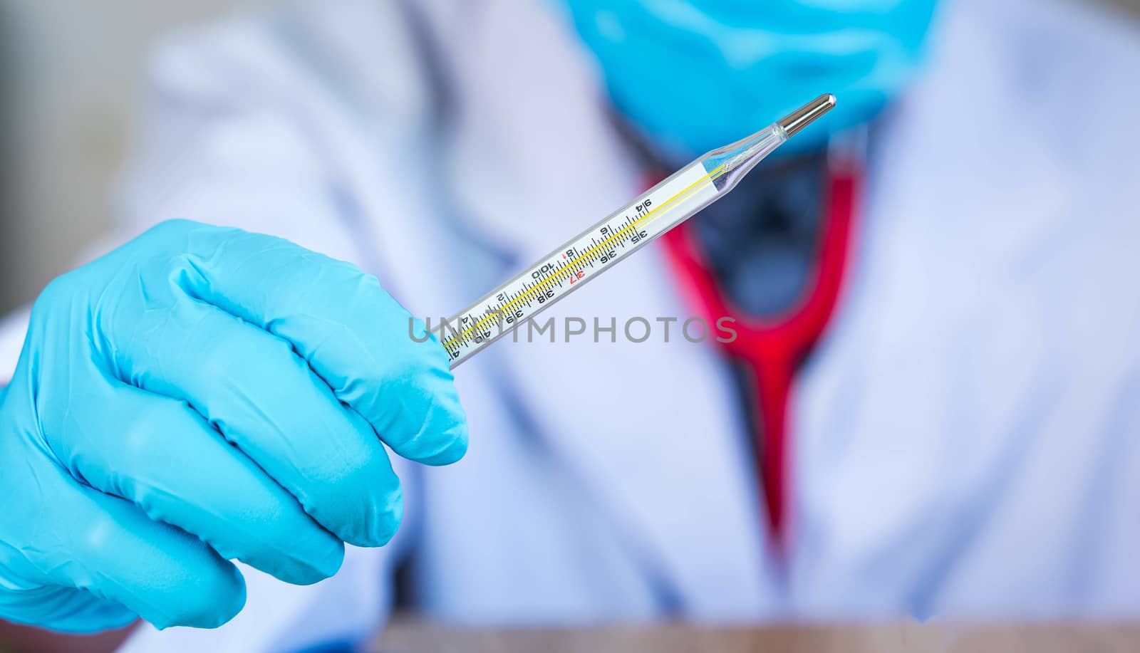 The doctor's hand is holding mercury to measure fever. To measure fever for patients in hospitals or clinics during the viral outbreak surveillance infected or infectious concept with blur background