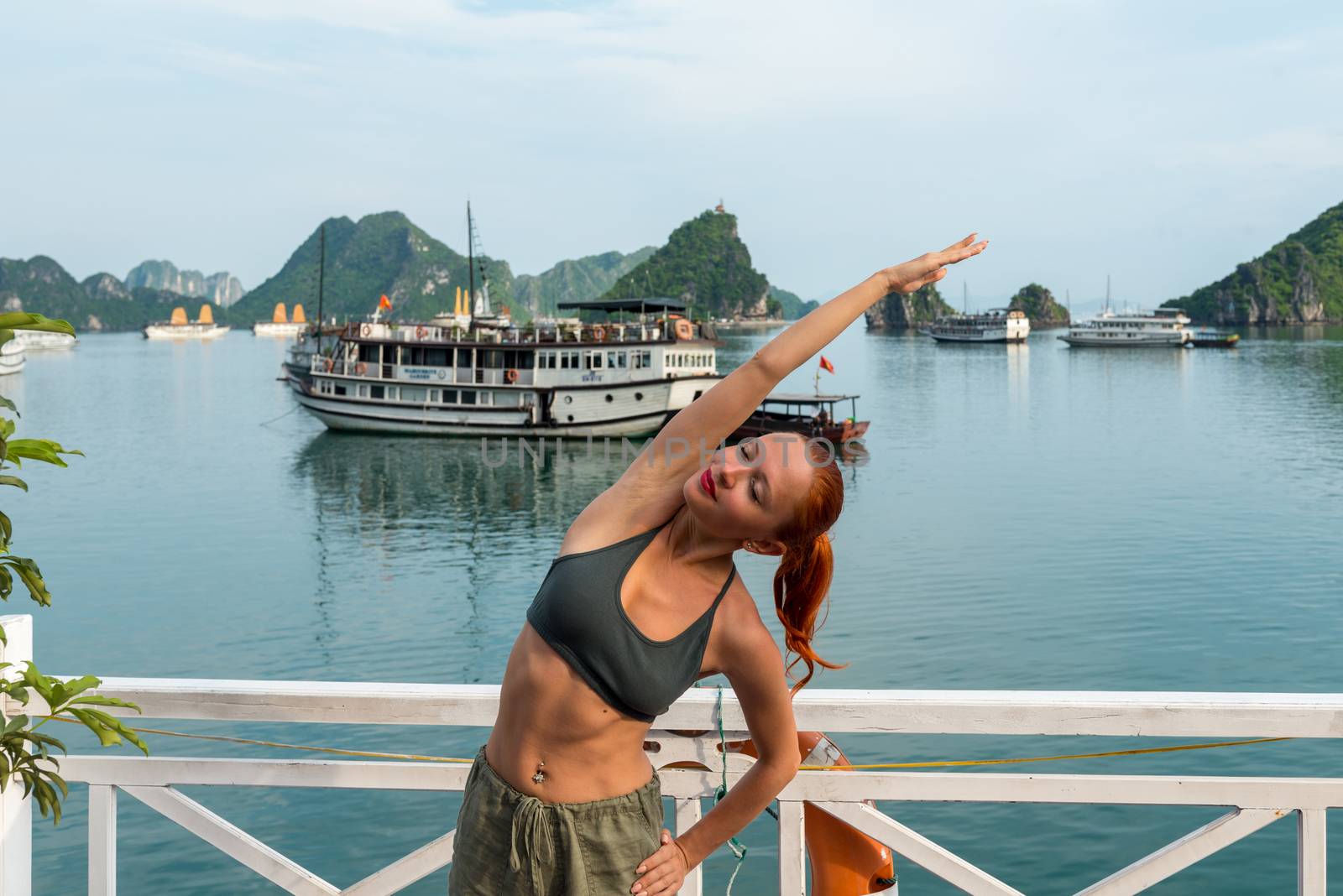 Young woman practicing yoga on the upper deck of ship. Morning time just after sunrise