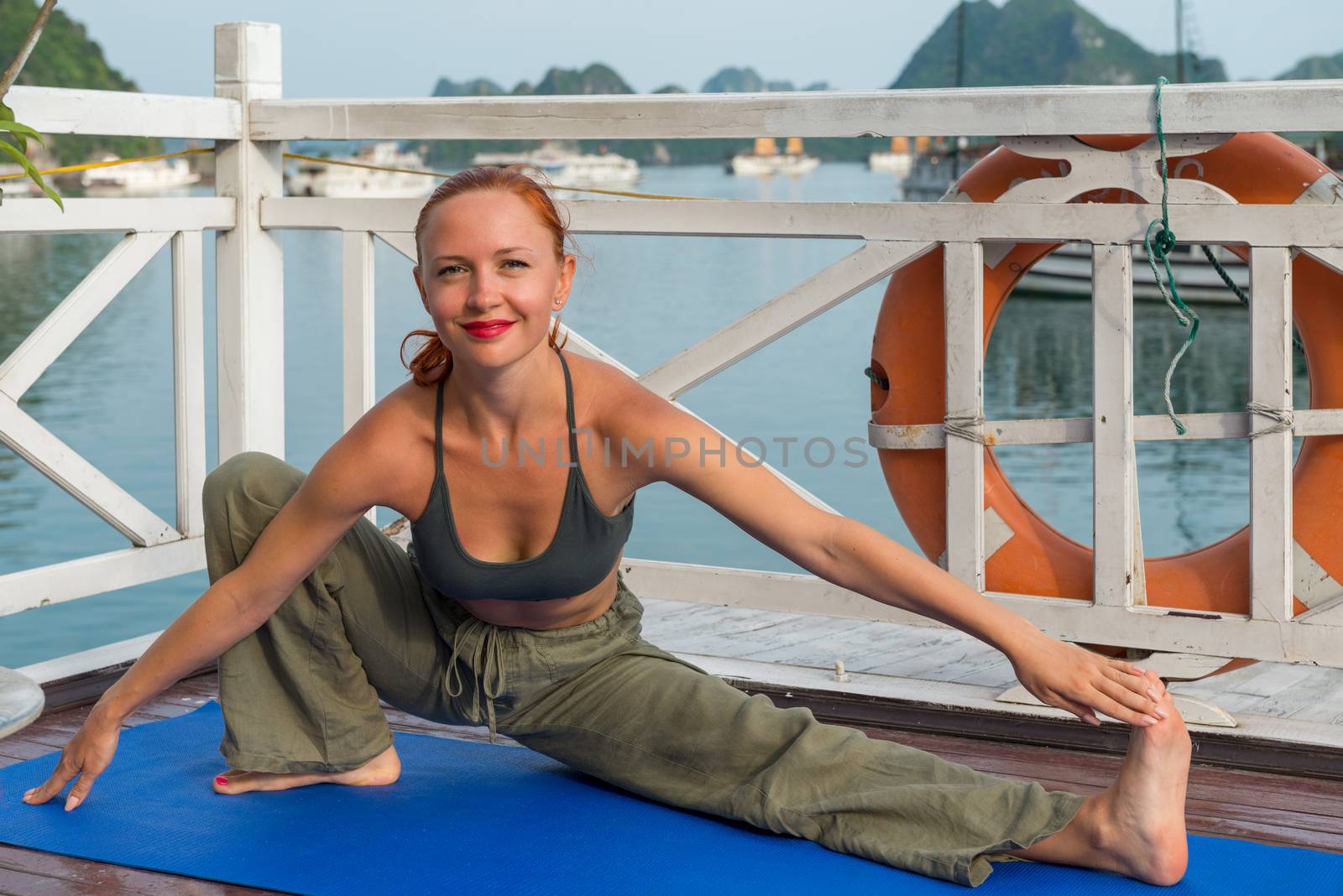 Young woman practicing yoga on the upper deck of ship. Morning time just after sunrise