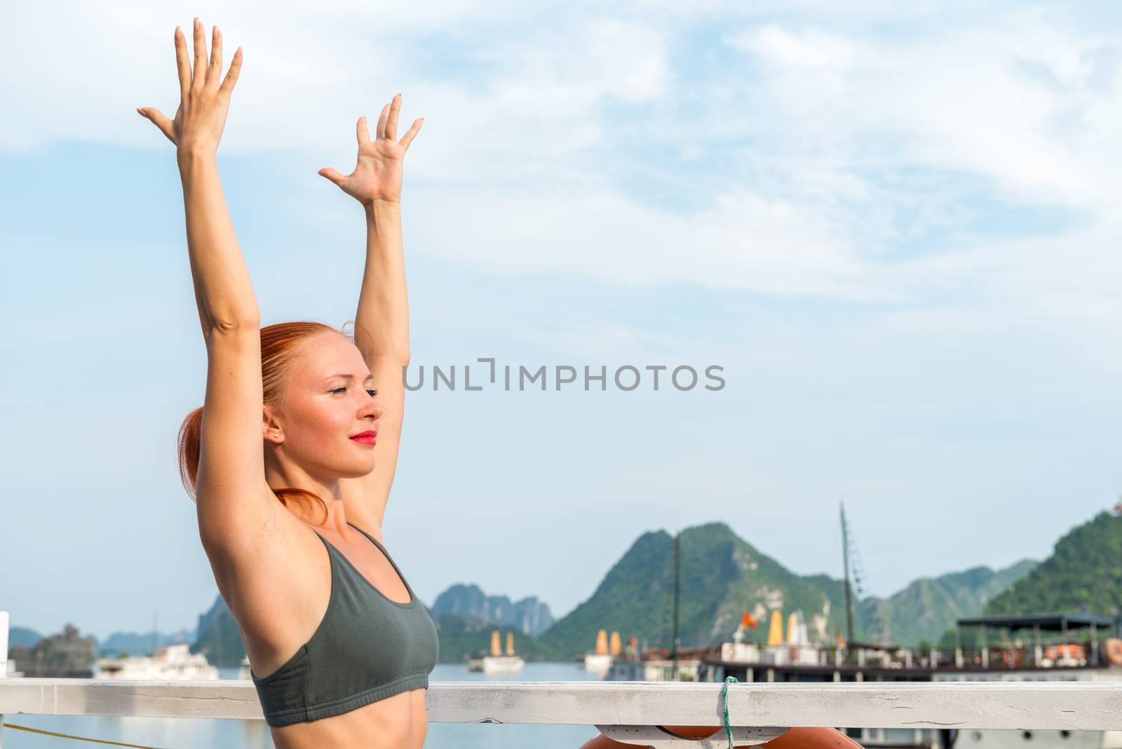 Young woman practicing yoga on the upper deck of ship. Morning time just after sunrise