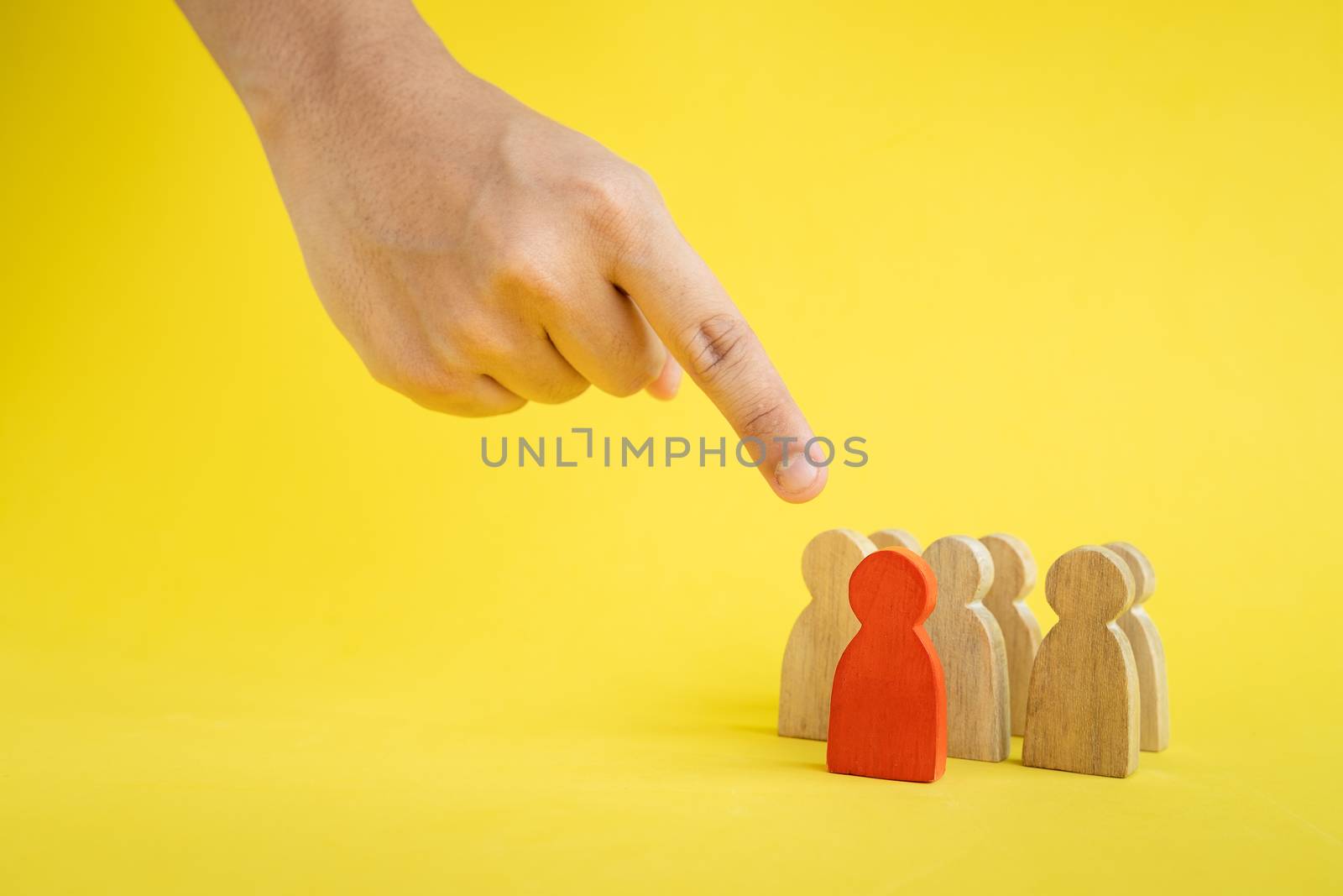 Group of wood figure hand pointing to the team leader in human resource management concepts Teamwork.Success Leadership, Business Progress and Competition on yellow backgrond and copy space
