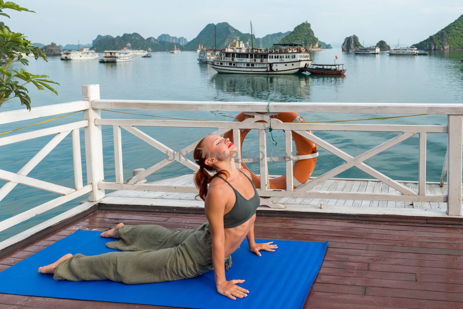 Young woman practicing yoga on the upper deck of ship. Morning time just after sunrise