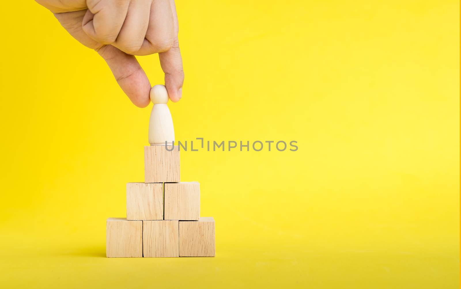 The hand is picking or select wood figure on the wooden Stacked in human resource management concepts Teamwork.Success Leadership,Business Progress and Competition on yellow backgrond and copy space