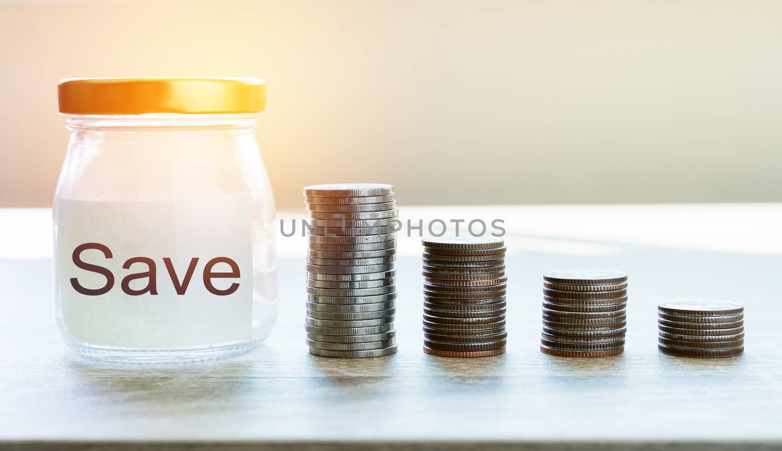 Money savings concepts. Put coins in glass bottles with paper label and text to spend on expenses such as savings, tourism, investment, emergency, retirement on wooden table with blur background