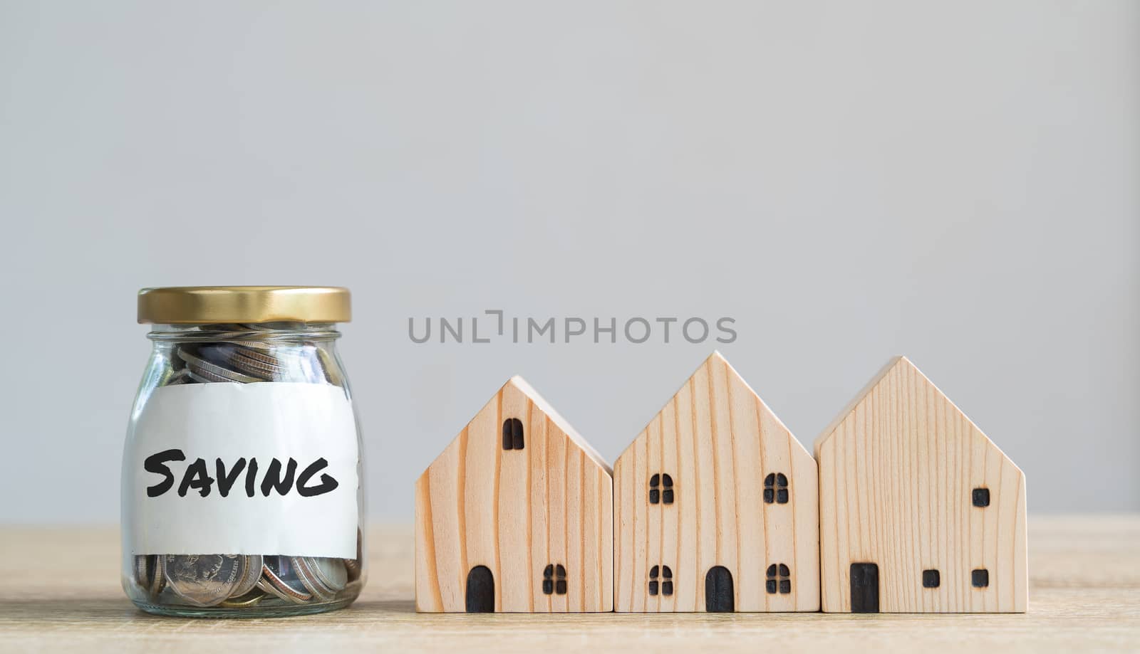 Money savings concepts. Wooden house models with coins in bottle and saving label meaning about saving money to buy a house, refinancing, investment or financial on wooden table with copy space