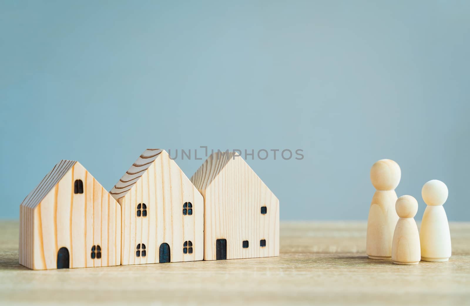 Money savings concepts. Wooden house models with family wooden dolls in meaning about saving money to buy a house, refinancing, investment or financial on wooden table with copy space