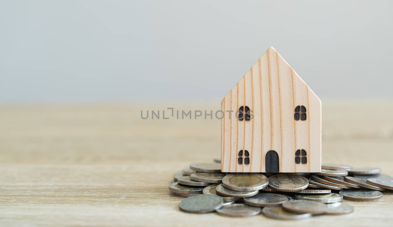 Money savings concepts. Wooden house models with coins in meanin by Boophuket