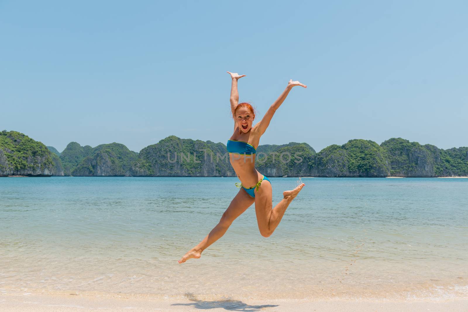 Fun girl wearing bikini jumping on a beach