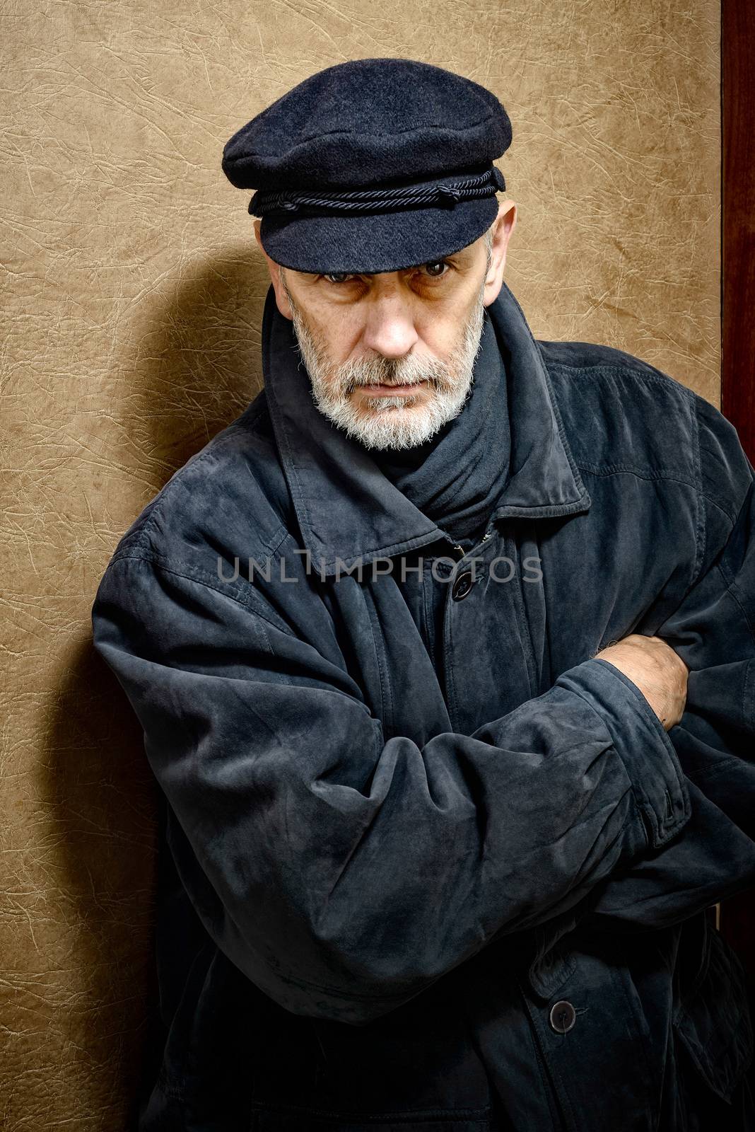 Portrait of a mature man with a white beard and a cap on the head. He could be a sailor, a worker, a docker, or even a gangster or a thug. He has a penetrating gaze.
