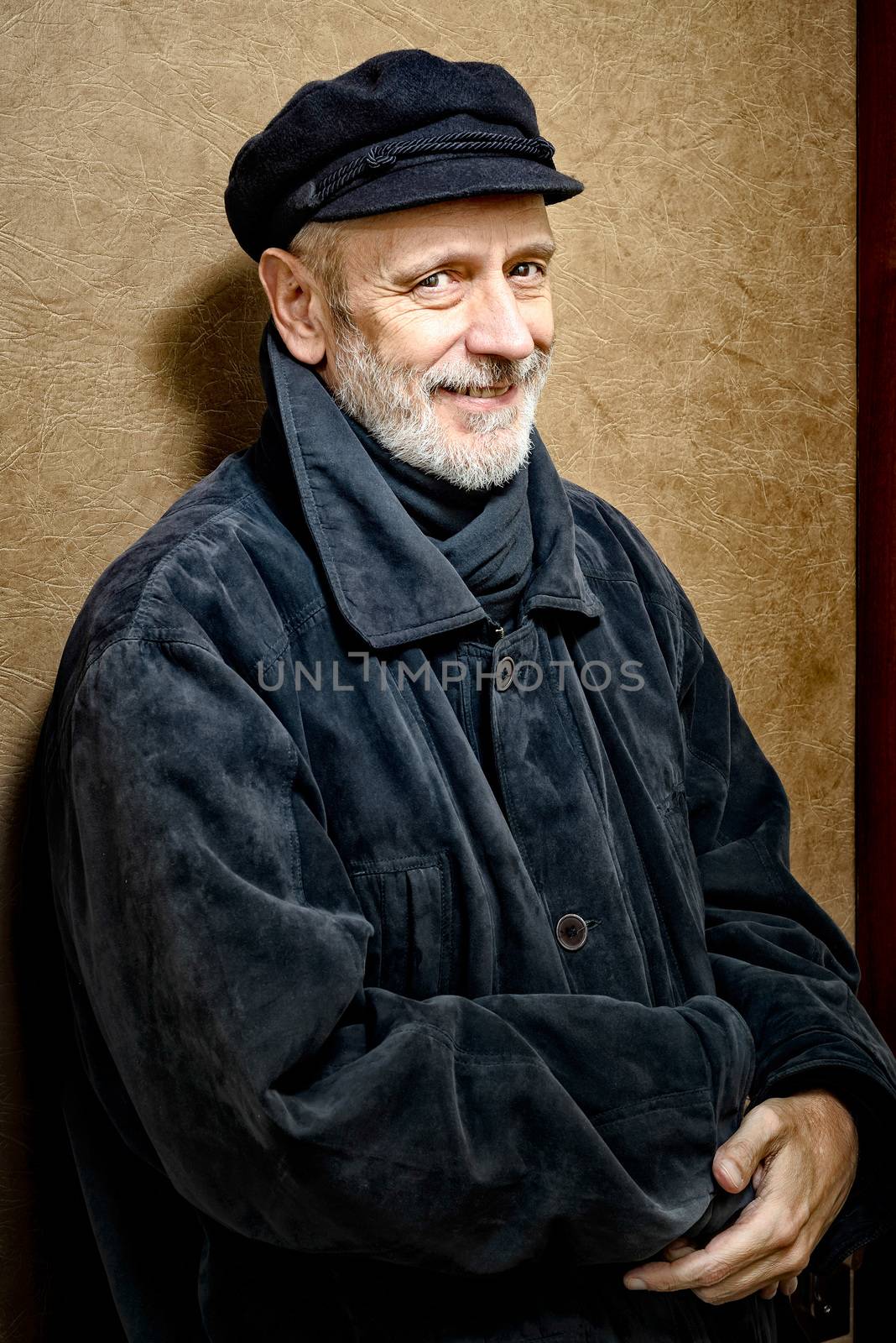 Portrait of a mature smiling man with a white beard and a cap on the head. He could be a sailor, a worker, a docker, or even a gangster or a thug. He has a penetrating gaze.