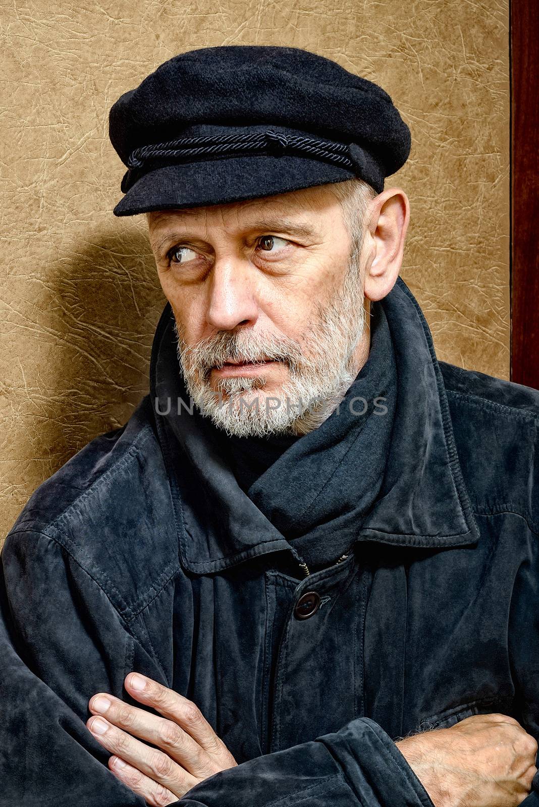 Portrait of a mature man with a white beard and a cap on the head. He could be a sailor, a worker, a docker, or even a gangster or a thug. He has a penetrating gaze.