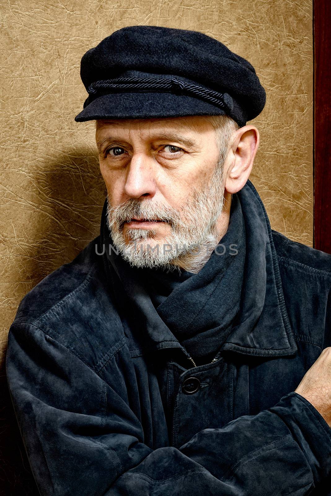 Portrait of a mature man with a white beard and a cap on the head. He could be a sailor, a worker, a docker, or even a gangster or a thug. He has a penetrating gaze.