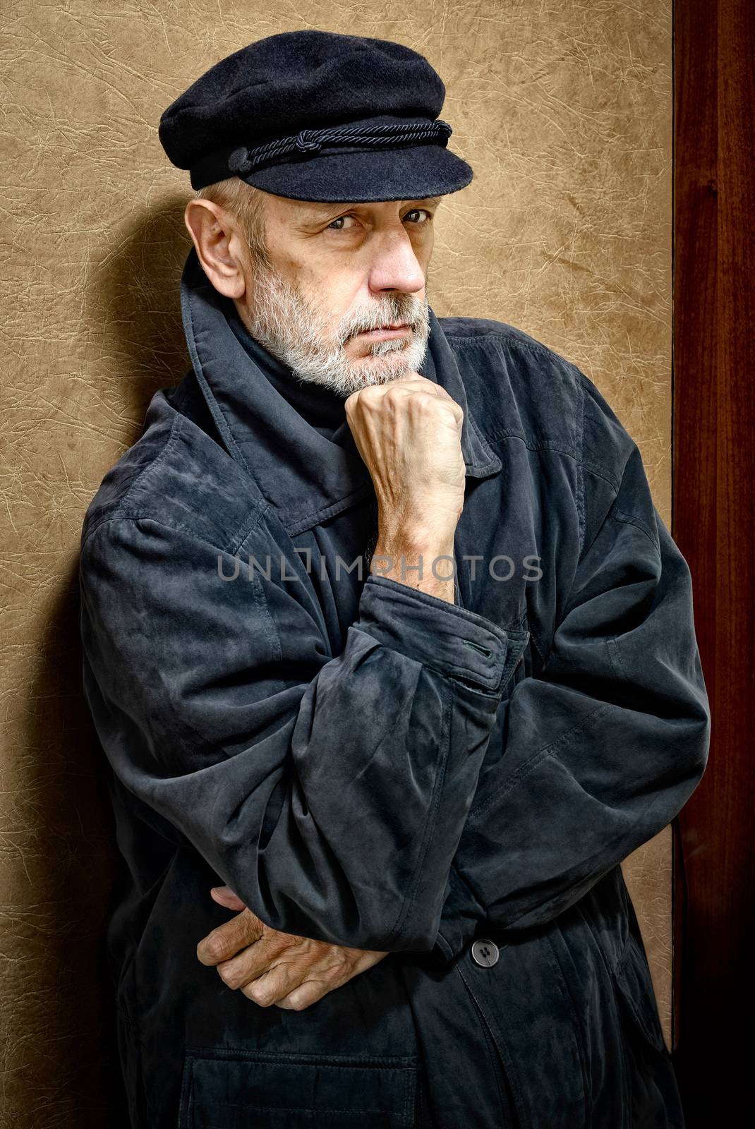 Portrait of a mature man with a white beard and a cap on the head. He could be a sailor, a worker, a docker, or even a gangster or a thug. He has a penetrating gaze.