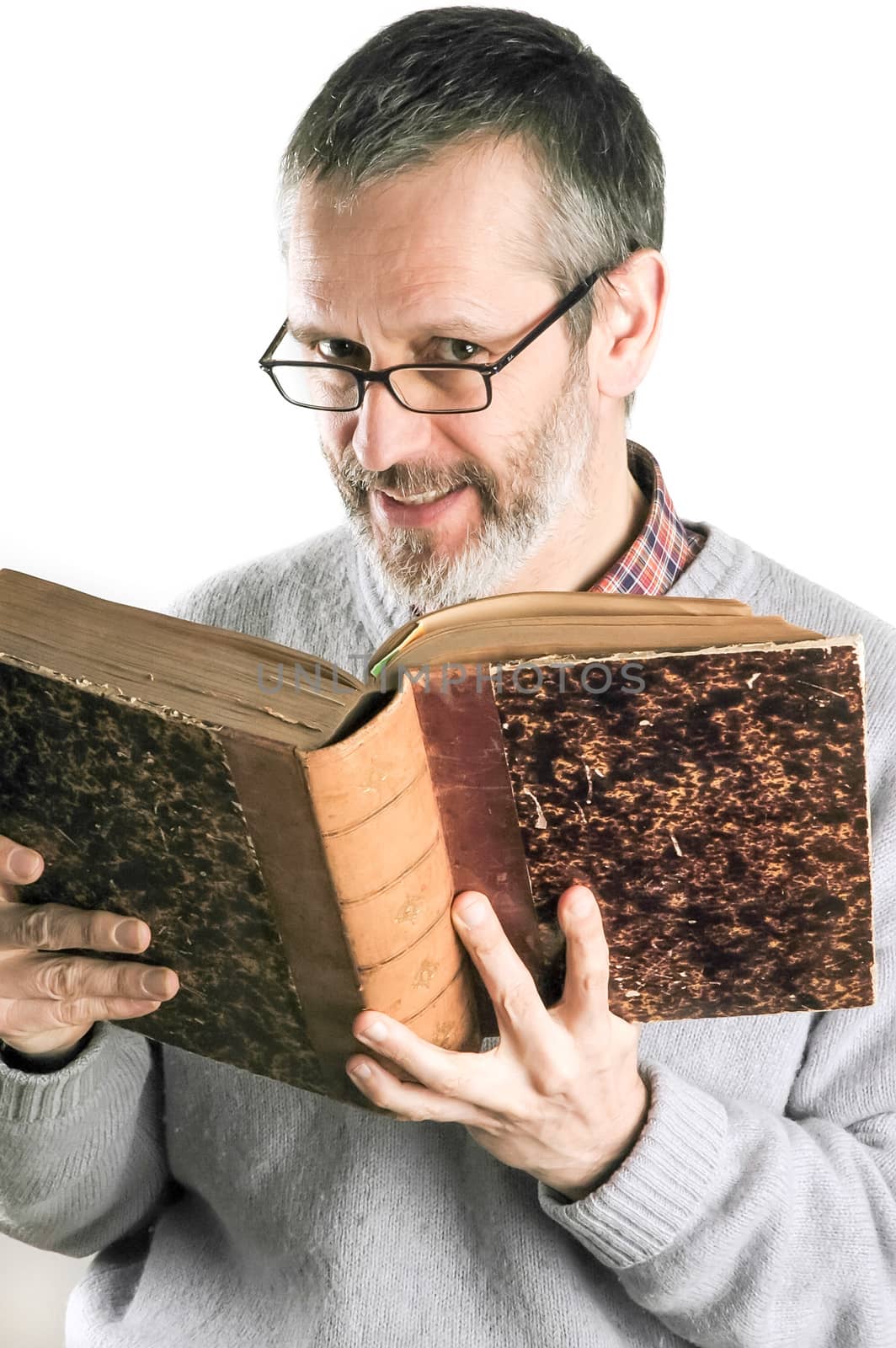 A smiing man reading an old book and wearing glasses
