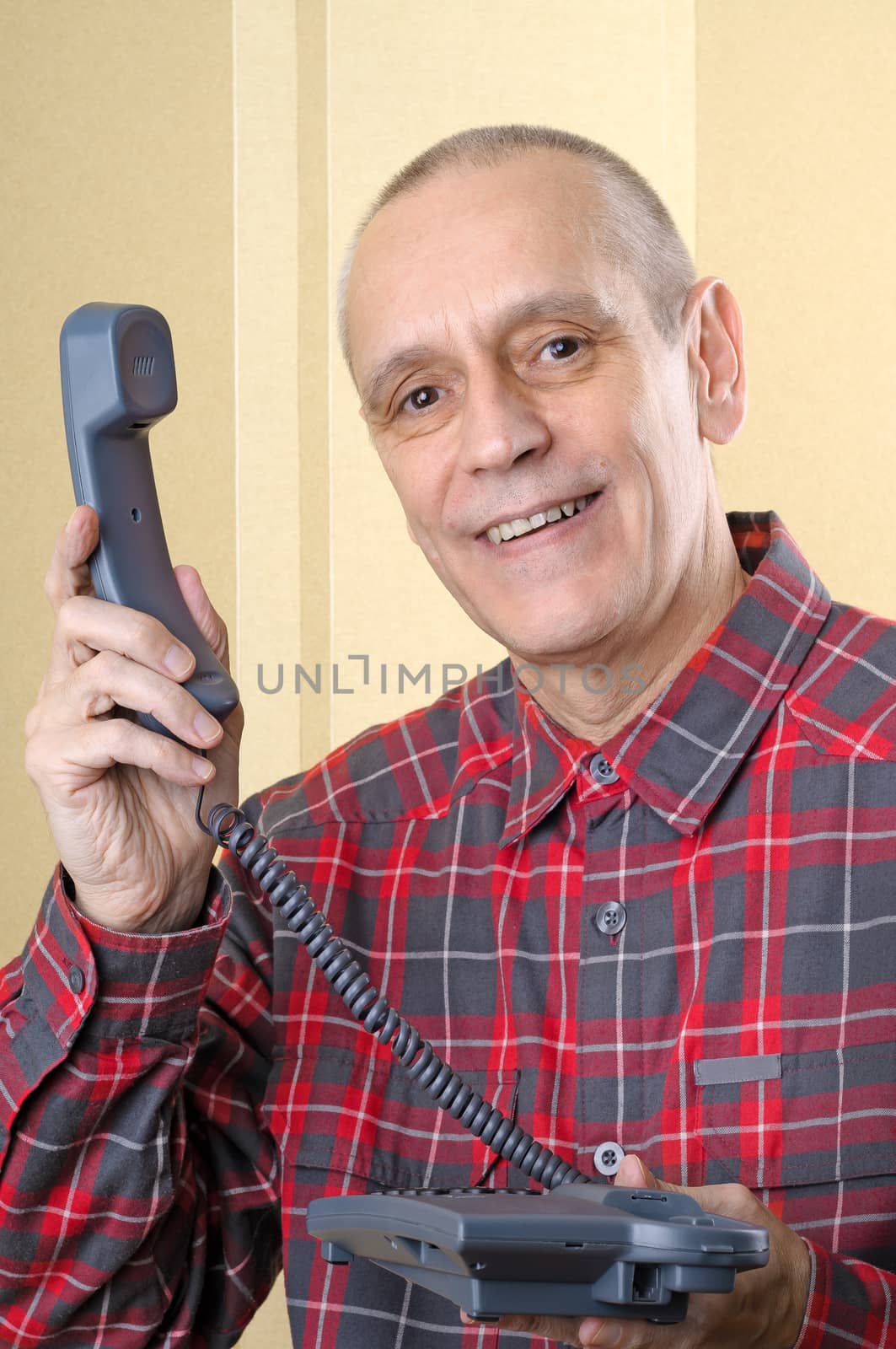 A senior man giving the phone handset to somebody else - There is a call for you!