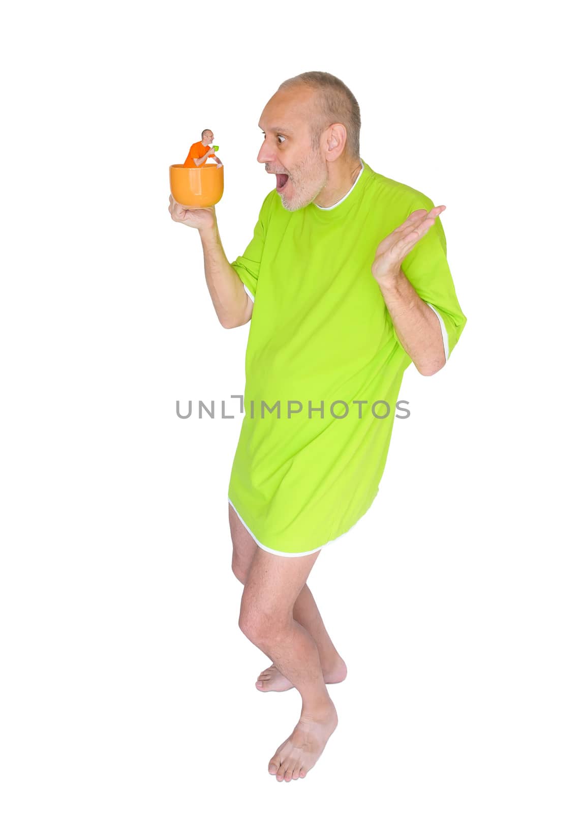 A man in green nightdress surprised to see himself in his cup of coffee or herbal tea