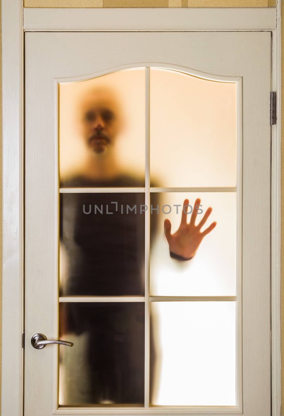 Silhouette of an unknown man in black  seen through a closed glass door, like a ghost or an alien