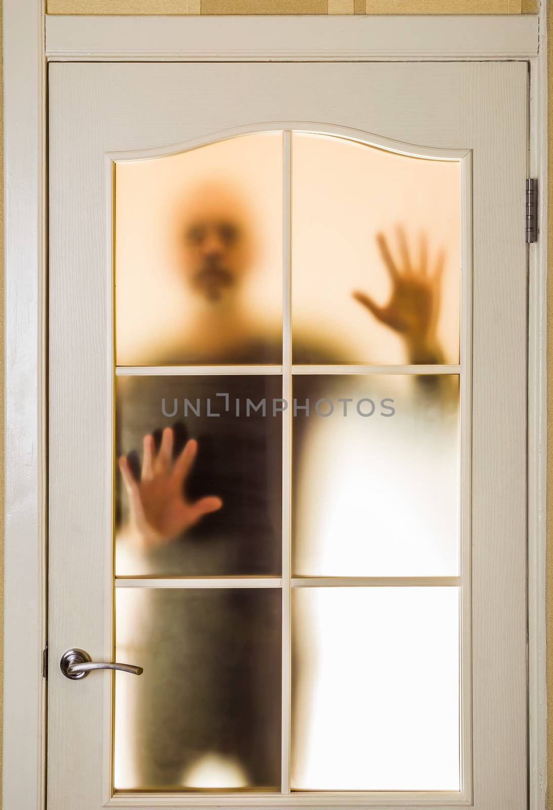 Silhouette of an unknown man in black  seen behind a closed glass door, like a ghost or an alien