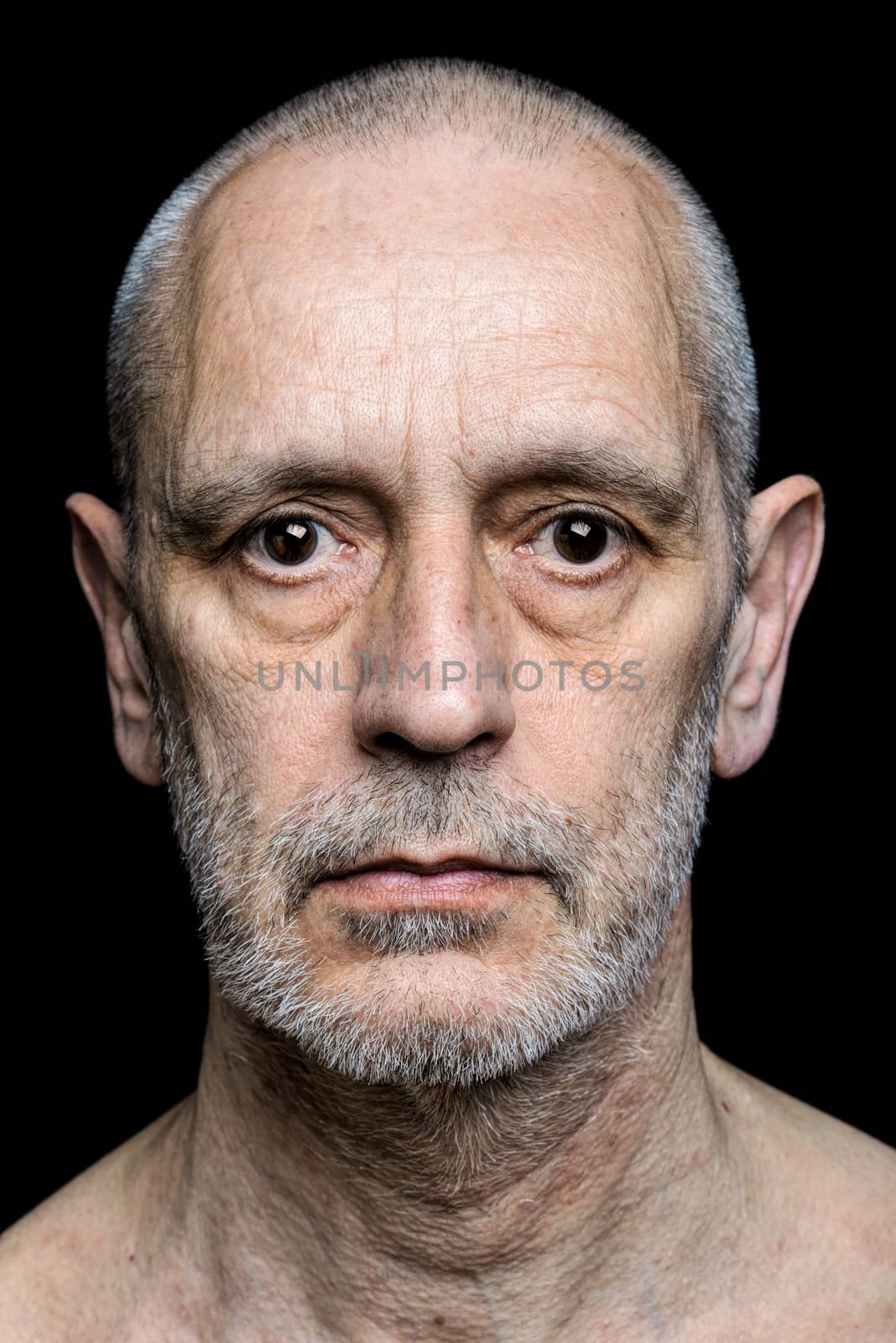 Dramatic color portrait of an adult man with sad expression on black background