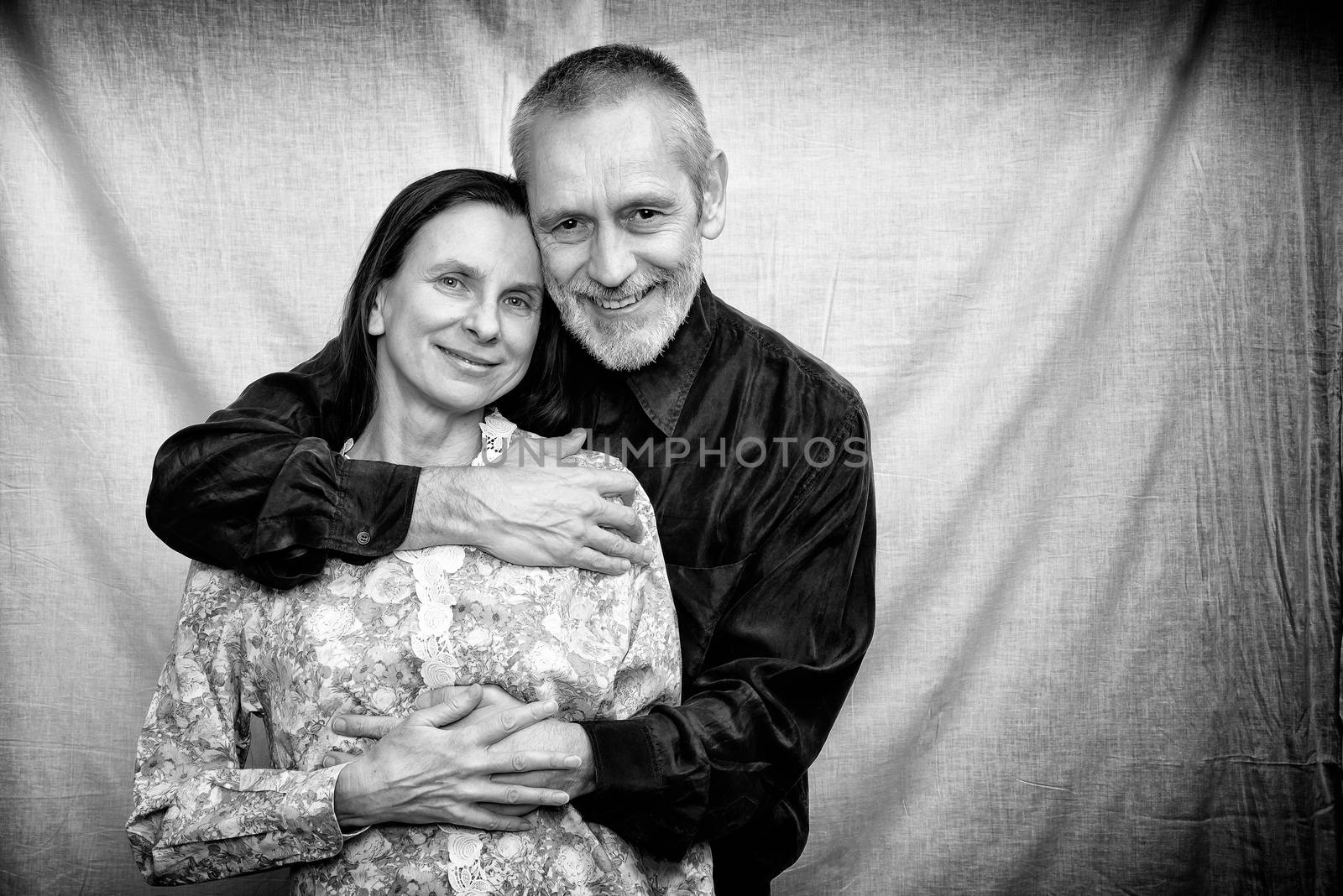 Happy mature man and woman smiling for S. Valentine's day or anniversary and embracing each other. Black and white photo.