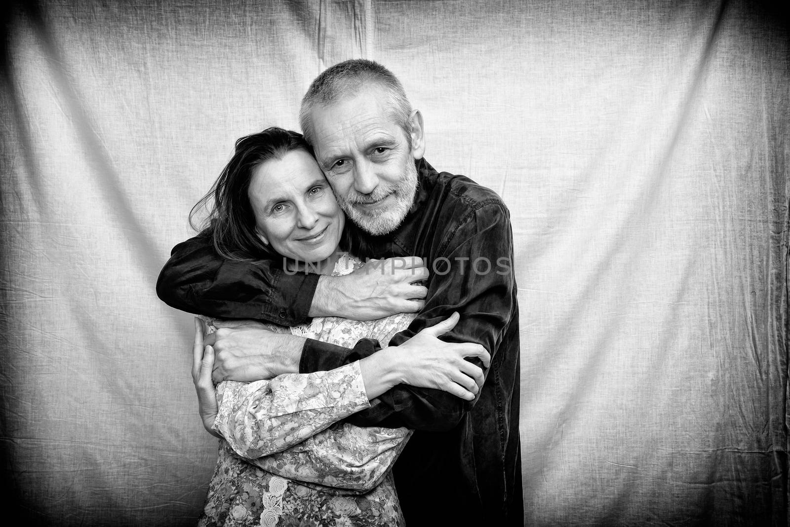 Happy mature man and woman with long hair smiling for S. Valentine's day or anniversary and embracing each other. Black and white photo.