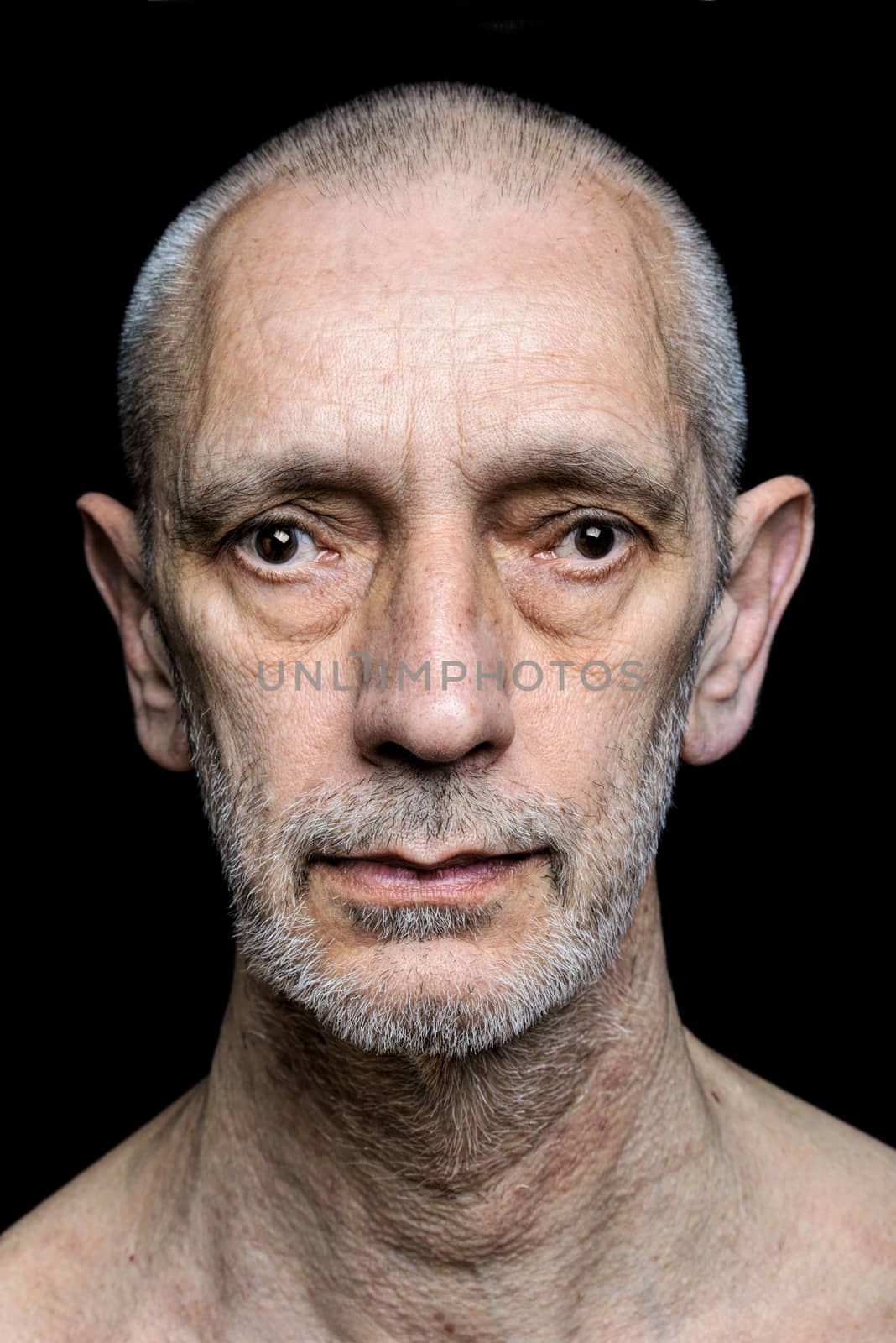Dramatic color portrait of an adult man with sad expression on black background