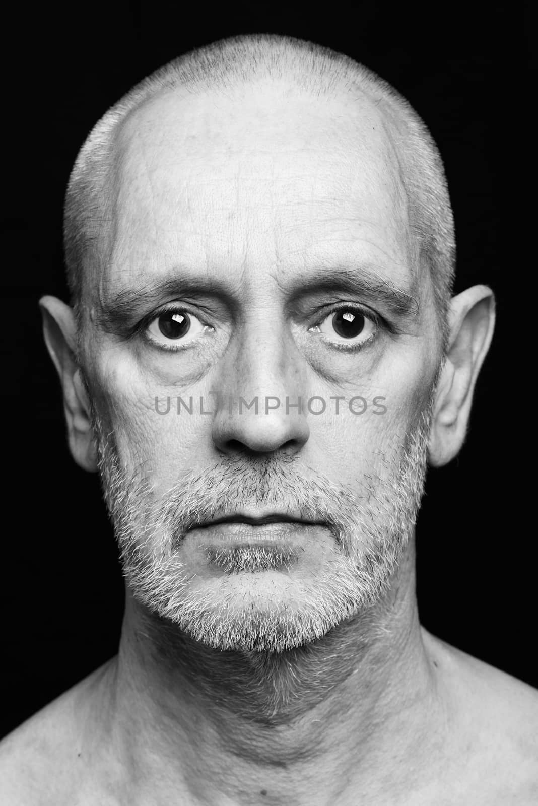 Dramatic black and white portrait of an adult man with sad expression on black background