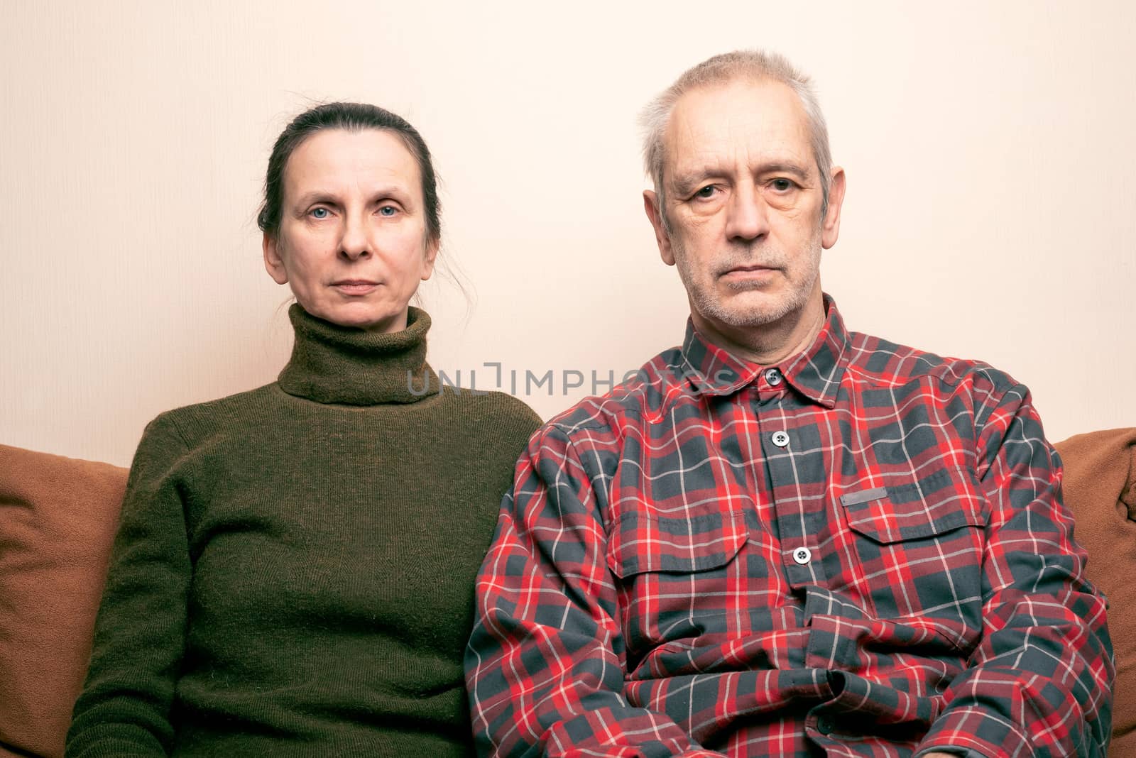 Dramatic portrait of sad and depressed adult woman and man sit on a sofa and  looking into space with lackluster eyes. Negative space for copy text