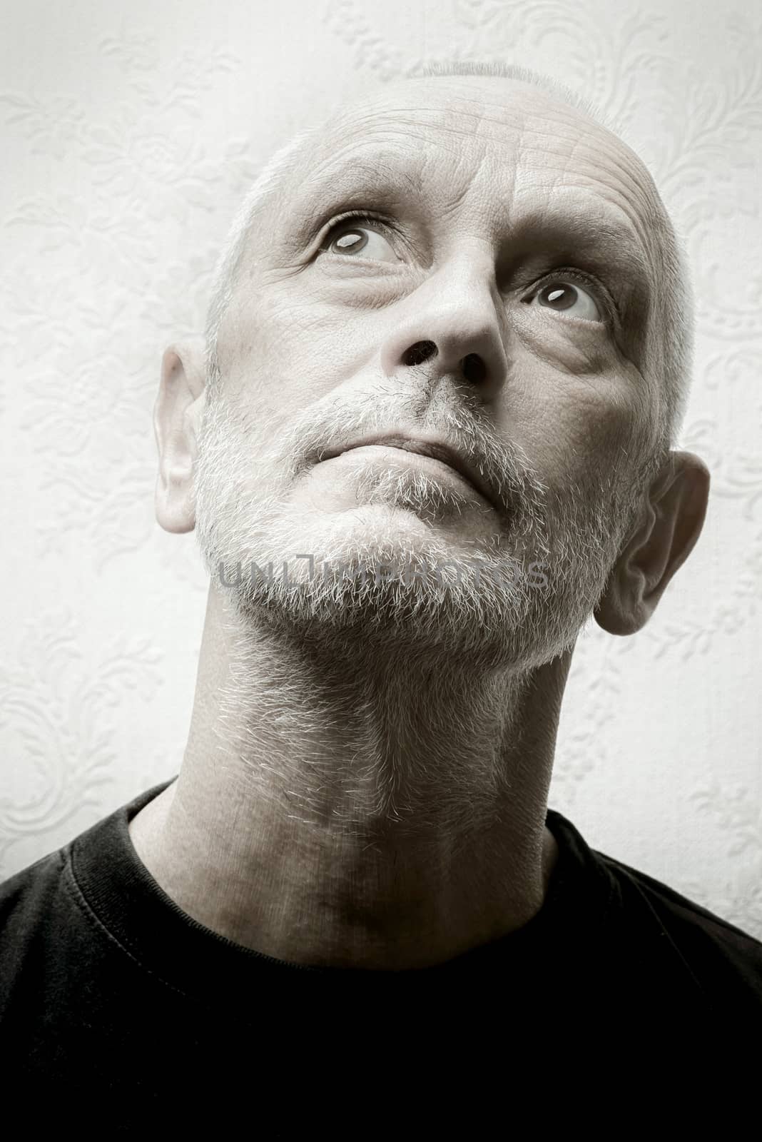 Black and white portrait of an inquiring caucasian adult gentle man with eyes looking up