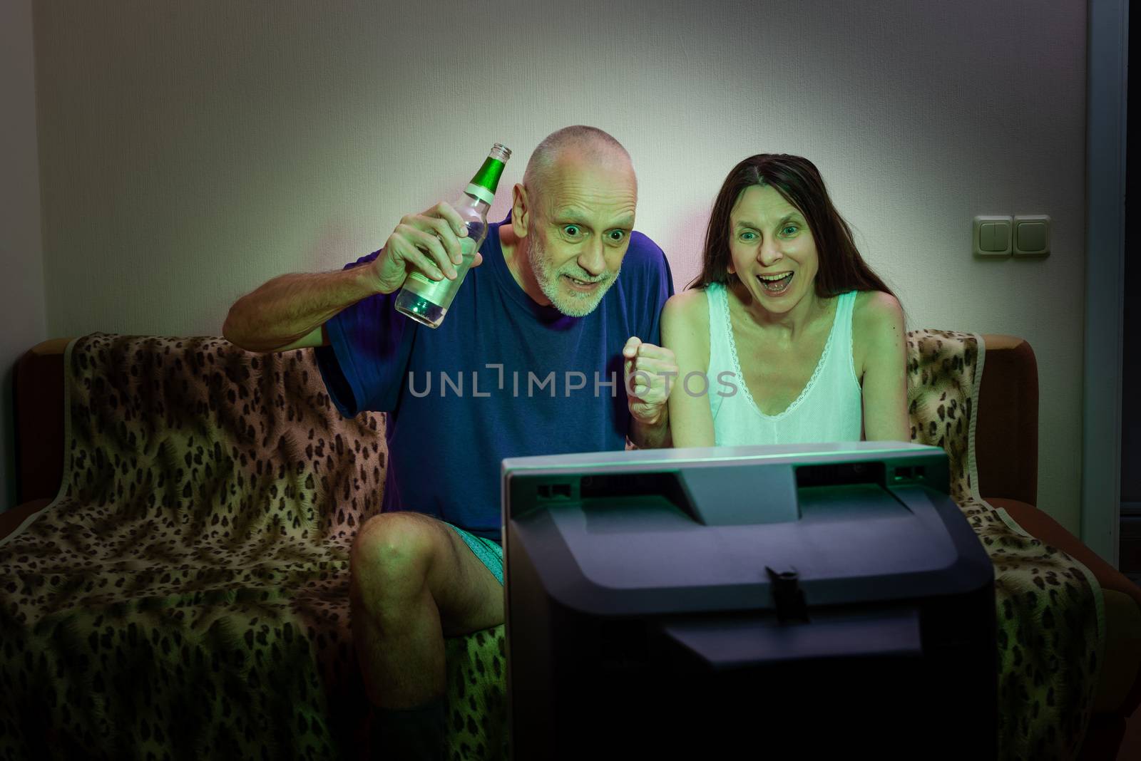 Adult man and woman watching sports on television by MaxalTamor